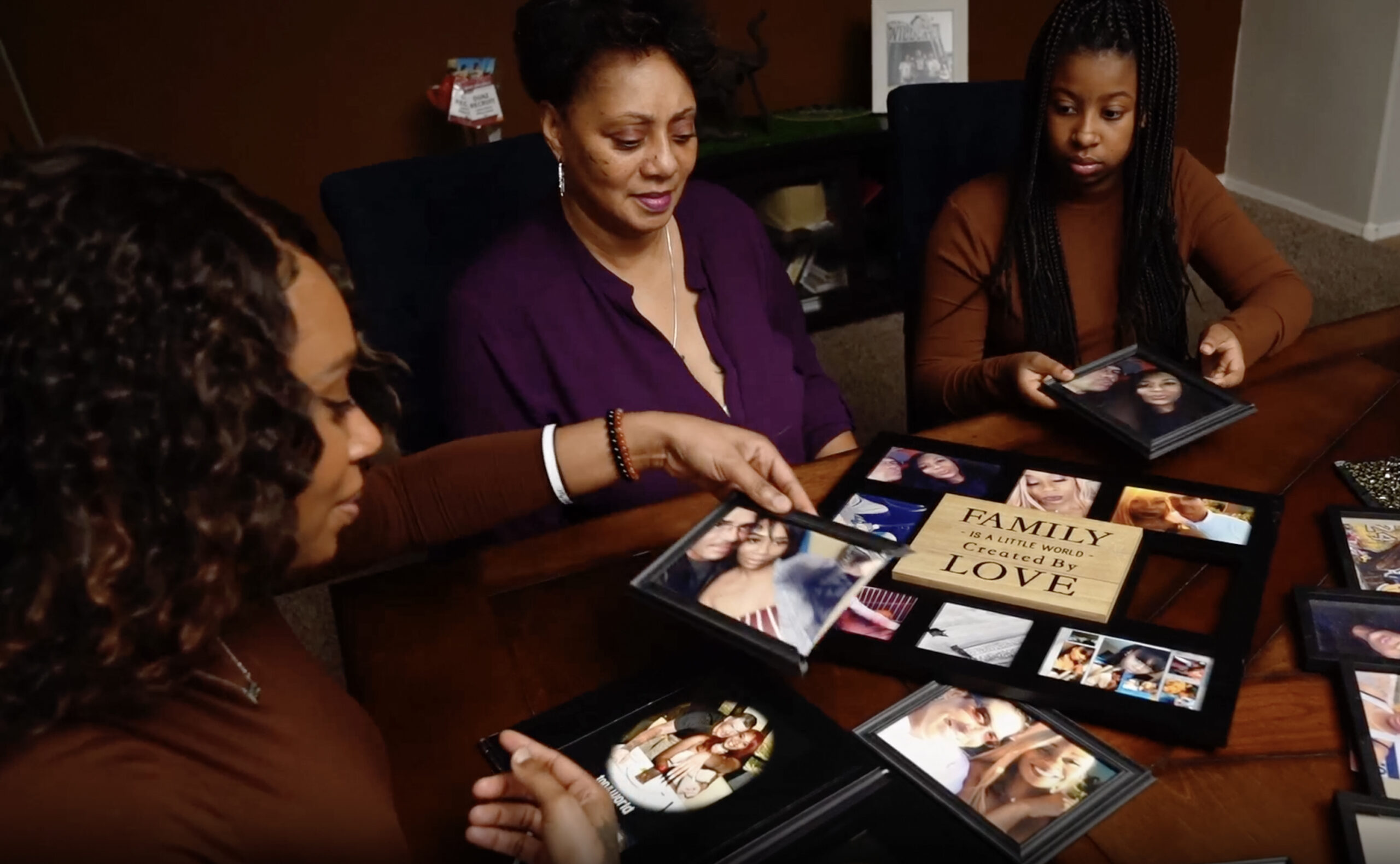 A family gathered around the table looking at framed photographs together.